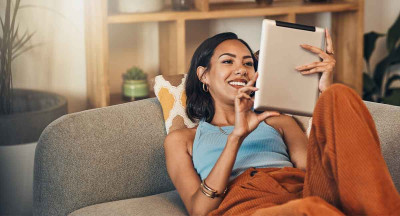 Femme utilisant une tablette dans son canapé